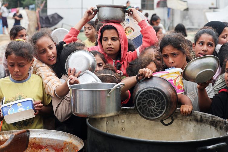 Ramadan Abed Palestinos aguardam para receber comida preparada por uma cozinha comunitária, em Nuseirat, Faixa de Gaza 08/04/2025 REUTERS/Ramadan Abed